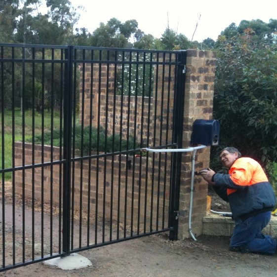 workman fixing a black automated gate